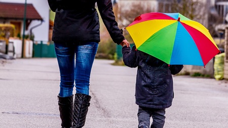 Mutter und Kind mit Regenschirm, Symbol für Solidarität, Hilfe, Hilfspaket, Rettungsschirm